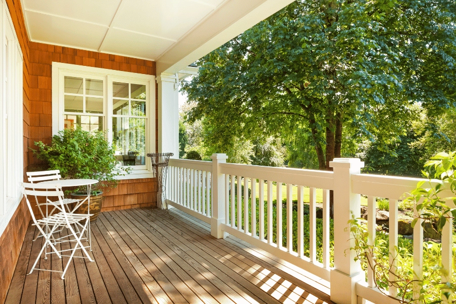 beautiful home with front porch with white seats and table and greenery